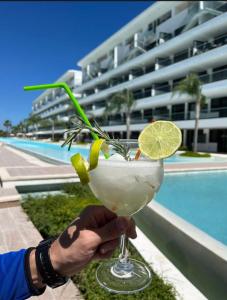 a person holding a drink in front of a pool at Cana Rock Star luxury condo, Casino, golf, beach in Hard Rock área in Punta Cana