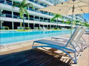 a lounge chair with an umbrella next to a swimming pool at Cana Rock Star luxury condo, Casino, golf, beach in Hard Rock área in Punta Cana