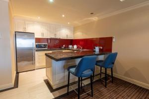 a kitchen with a refrigerator and two blue bar stools at Apartment 4, 9 River Lane Mannum in Mannum