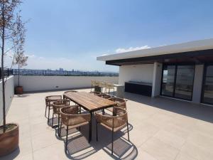 a patio with a table and chairs on a roof at Departamento Puesta del Sol Gdl in Guadalajara