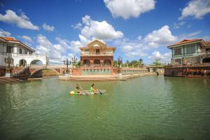 two people in a paddle boat in a river with a bridge at Las Casas Filipinas de Acuzar in Bagac