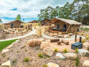 a house with a tent in a yard with rocks at Glamping 148 Tasmania in St Helens