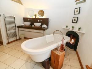 a bath tub in a bathroom with a fireplace at Castle Combe Cottage in Castle Combe +42 photos