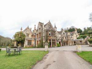 an old mansion with a table and chairs in the driveway at Castle Combe Cottage in Castle Combe