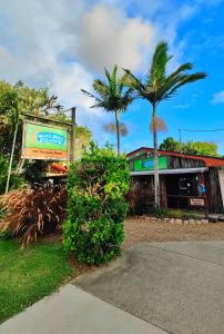 a building with a sign and palm trees in front of it at Woolshed Eco Lodge in Hervey Bay