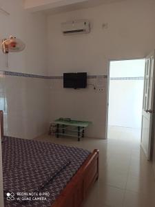 een slaapkamer met een bed en een tv aan de muur bij Nhà nghỉ Thiên Thanh 1 in Long Hai