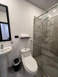 a bathroom with a toilet and a glass shower at Katara Boutique Hotel in Mariquita