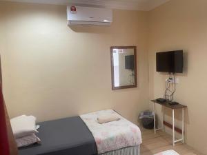 Dormitorio pequeño con cama y TV en Wan Guesthouse, en Tumpat