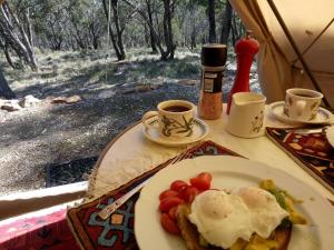 a plate of food with eggs and tomatoes on a table at Macedon Ranges Glamping in Macedon