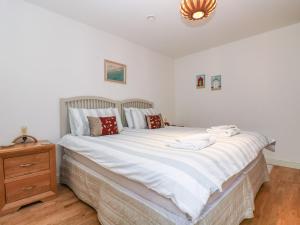 a bedroom with a large white bed and a wooden dresser at Ocean Blue in Penzance
