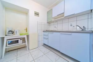 cocina blanca con fregadero y microondas en Apartments Jelen, en Dubrovnik