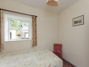 a bedroom with a bed and a window and a chair at Bank Top Cottage in Hathersage
