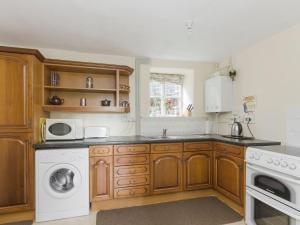 a kitchen with wooden cabinets and a washer and dryer at Bank Top Cottage in Hathersage