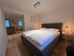 una camera da letto con un grande letto bianco con lenzuola bianche di Apartmenthaus Wagner a Möckmühl