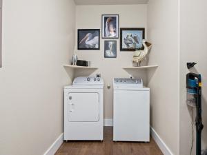 a laundry room with two washing machines and pictures on the wall at Port Royal Dream in City-by-the Sea +21 photos