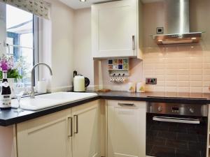 a kitchen with white cabinets and a sink and a window at Dairy Cottage in Matfield