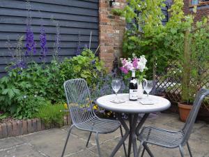 a table and two chairs with wine glasses and flowers at Dairy Cottage in Matfield