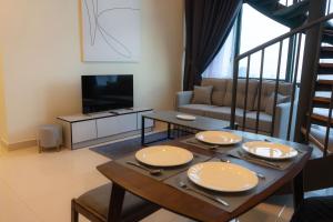 a living room with a table and a television at StaySuites The Apple Melaka in Melaka