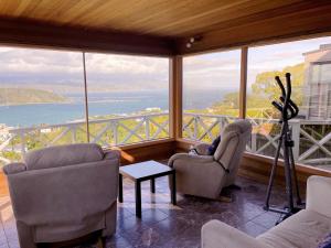 Sala de estar con 2 sillas y vistas al océano en NO PARTY ALLOWED,Sea view 5 bedroom house, en Wellington