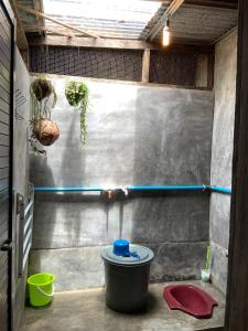 a small bathroom with a bucket and a wall at Homestay Bukit Lawang in Bukit Lawang
