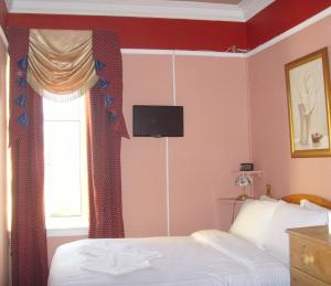 a bedroom with a bed with a television on the wall at Twin Lions Hotel in Edinburgh