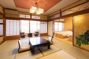 a room with a table and a bed and windows at Kadojin in Tenkawa