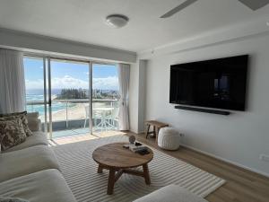 a living room with a couch and a tv and a table at Endless Summer in Cooly Level 18 in Gold Coast