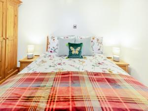 a bed with a colorful comforter and two lamps at Piglets House - Uk43488 in Aldington