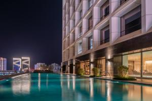 a swimming pool in front of a building at night at Sofitel Haikou in Haikou