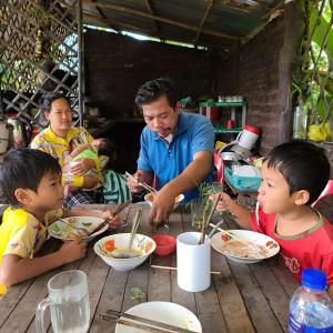 um grupo de pessoas sentadas à volta de uma mesa a comer em Phonluer Angkor Homestay, em Siem Reap