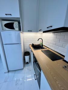eine Küche mit einer Spüle und einem weißen Kühlschrank in der Unterkunft Modern 1-bedroom apartment in the city center in Thessaloniki