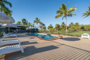 een zwembad met twee witte banken en palmbomen bij Kinka Palms Motel in Kinka
