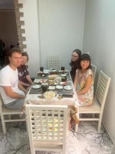 un gruppo di persone seduti intorno a un tavolo con cibo di Hamida a Samarkand