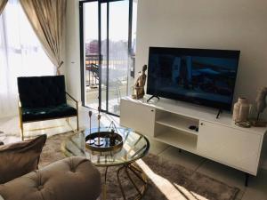 a living room with a flat screen tv on a white cabinet at Luxury beach lagoon 1 Bedroom apartment in Pretoria
