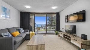 sala de estar con sofá y TV en Beachpark Apartments - Close To Beach en Port Macquarie