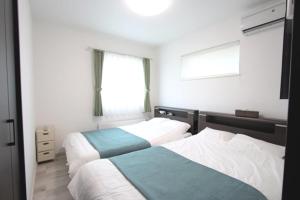 sypialnia z 2 łóżkami i oknem w obiekcie TEINE WHITE HOUSE w mieście Sapporo