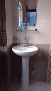 ein Badezimmer mit einem weißen Waschbecken und einem Spiegel in der Unterkunft Mountainshade Home in Kathmandu