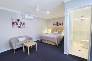 a bedroom with a bed and a chair and a toilet at Nebula Motel in Cooma