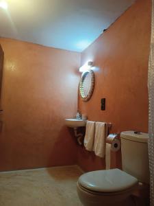 une salle de bain avec toilettes, lavabo et miroir dans l'établissement kasbah Dar Bahnini, à Skoura