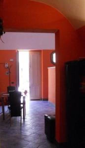 een woonkamer met oranje muren en een tafel en stoelen bij Dammuso SoleLuna. in Terrasini