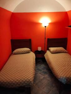- 2 lits dans une chambre aux murs rouges dans l'établissement Dammuso SoleLuna., à Terrasini