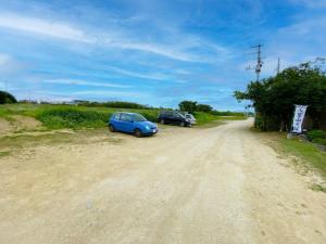 un coche azul estacionado al lado de un camino de tierra en House&Cafe GreenTerrace, en Ishigaki Island