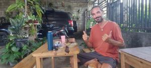 a man sitting on a table giving thumbs up at Akria Bed and breakfast in Bayan +22 photos