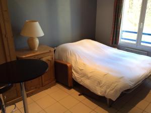 a bedroom with a bed with a lamp and a table at Residence Hotel Les Ducs De Chevreuse avec Hébergement, Repas & PDJ, Séminaire, Bureau & Parking in Chevreuse