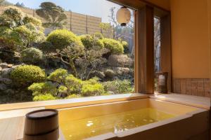 a bath tub in a window with a view of a garden at Kadojin in Tenkawa