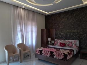 a bedroom with a bed and two chairs and a window at Orchid Ranipuram in Kallar +7 photos