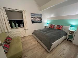1 dormitorio pequeño con 1 cama y 1 sofá en Ferienhaus Ooghduyne 33 en Julianadorp