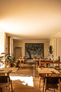 a dining room with tables and a large painting on the wall at Hôtel Le Mosaïque in Narbonne