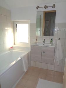 een witte badkamer met een bad en een wastafel bij Belvárosi allódium tetőterasszal in Szentendre