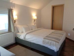 1 dormitorio con 1 cama grande con sábanas blancas y ventana en Belvárosi allódium tetőterasszal, en Szentendre
